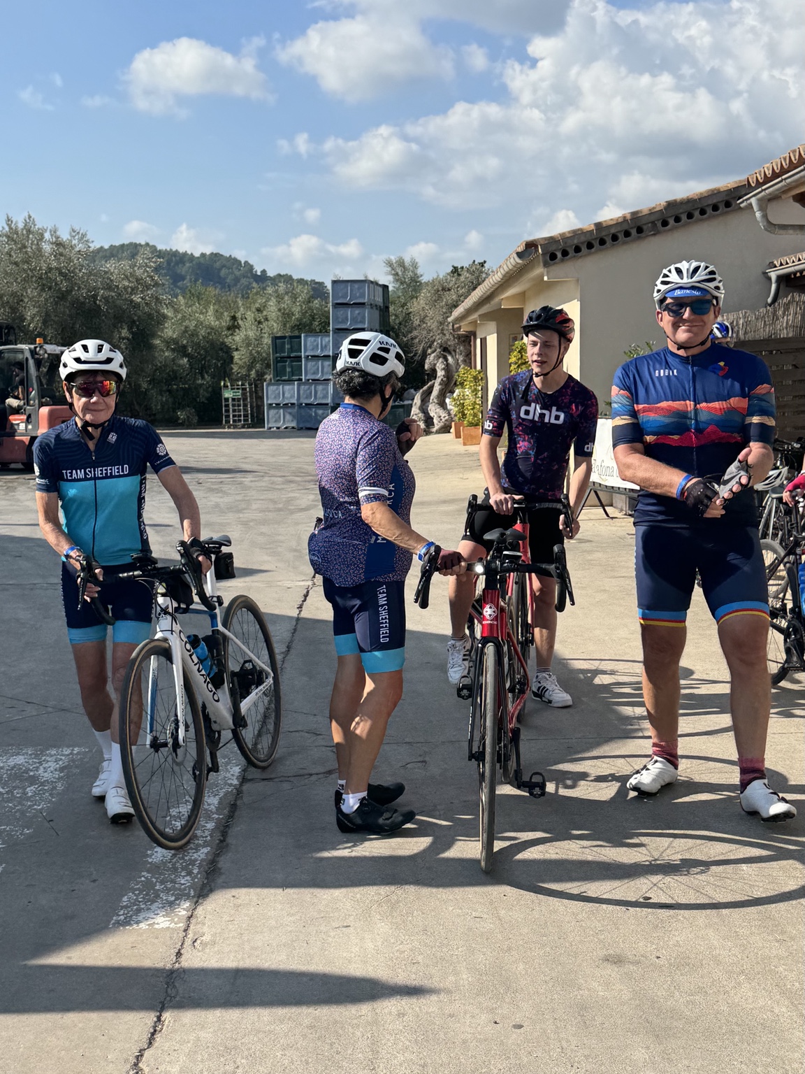 Four cyclists gathering with their bikes outside a café